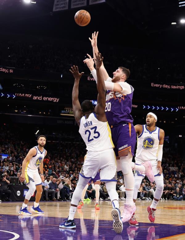 Jusuf Nurkic #20 of the Phoenix Suns puts up a shot over Draymond Green #23 of the Golden State Warriors during an NBA game at Footprint Center on December 12, 2023 in Phoenix, Arizona.  